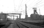 Unmittelbar gegenüber vom „Schalker Verein“ befand sich gleich auch die Zeche Alma. Zwischen einem Gewirr von Versorgungsleitungen und Förderanlagen führte der wichtigste, mitten durch dasRuhrgebiet laufende Schienenweg gleichsam auch durch das Herz der Montanindustrie. Geballte Industrieatmosphäre dominiert daher die Szene bei der Vorüberfahrt der solo laufenden V 200. (1961) <i>Foto: Willi Marotz</i>