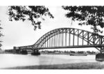 Zwischen 1916 und 1918 wurde die Brücke aus militärischen Gründen unter dem Namen "Kronprinz-Wilhelm-Brücke" oder "Kronprinzenbrücke" errichtet. Sie verband die rechte und linke Rheinstrecke zwischen Engers und Urmitz und war Teil einer Brückenfamilie aus drei ähnlichen, strategisch motivierten Eisenbahnbrücken über den Rhein, mit der Ludendorffbrücke in Remagen und die Hindenburgbrücke bei Rüdesheim. Nachdem diese Brücke im März 1945 von deutschen Truppen gesprengt wurde, wurde sie 1954 als Fachwerkbrücke wieder aufgebaut. (1931) <i>Foto: RVM</i>