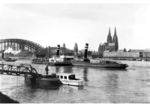 Blick von der Deutzer Rheinseite auf die Hohenzollernbrücke mit dem Kölner Dom. Vor dem Dom ist das im Krieg zerstörte Verwaltungsgebäude der ehem. Rheinischen Eisenbahngesellschaft zu erkennen (Bj. 1856), rechts daneben das Geschäftsgebäude der Direktion (Bj. 1912). Auf dem Rhein schwimmt das Dampfschiff "Carl Huber" der Raab Karcher Gesellschaft. (1934) <i>Foto: RVM</i>