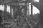Nachdem der unterstromseitige Brückenzug wiederhergestellt wurde, konnte der Oberbau für das 3. und 4. Brückengleis auf der Hohenzollernbrücke mit Hilfe eines Ardelt 10t Gleisbau Kranwagen verlegt werden. Links passiert 03 074 die Szenerie. (17.04.1959) <i>Foto: Fischer</i>