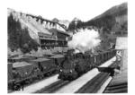 97 210 läuft mit Schiebelok und einem beladenen Erzzug in den Bahnhof Präbichl (Obersteiermark) ein. Im Hintergrund die Erzverladeanlage. Die Erzbergbahn verbindet die Südbahnstrecke (Leoben) mit der Rudolfsbahn (Hieflau). Der mittlere Abschnitt zwischen Vordernberg und Eisenerz wurde über den 1204 m hohen Präbichl als Zahnradstrecke geführt. (1938) <i>Foto: RVM</i>