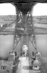 Einmalig in Deutschland dürfte die 1913 in Betrieb genommene Schwebefähre unter der Rendsburger Hochbrücke über den Nord-Ostseekanal sein. Vier 35 m lange Trageseile und acht gekreuzte Versteifungsseile halten die 14 m lange und 6 mbreite Fähre an einem Fährwagen. Dieser hängtunter der Hochbrücke und wird mit vier Motoren angetrieben.  (03.07.1955) <i>Foto: Walter Hollnagel</i>