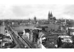 Das Kölner Altstadtpanorama mit der von 1913 bis 1915 errichteten „Deutzer Hängebrücke“, die 1935 nach dem Reichspräsidenten Paul von Hindenburg in "Hindenburgbrücke" umbenannt wurde.Sie wurde als versteifte Kettenhängebrücke durch die MAN, Werk Gustavsburg, in Nickelstahl mit einem Konstruktionsgewicht von rund 6.200 Tonnen ausgeführt und kostete über 7 Millionen Mark. Die architektonische Gestaltung der massiven Bauteile (Widerlager und Vorbrücke) besorgte der damals prominente Kölner Architekt Carl Moritz. Die 18,20 m breite Brücke wurde 1939/1940 auf 27,50 m verbreitert.Am 28. Februar 1945 brach die durch Flüchtlinge und Militärfahrzeuge hoch belastete Hindenburgbrücke bei der Reparatur von Kriegsschäden unvermittelt zusammen. Möglicherweise hatte man die hohen Druckkräfte im Fahrbahnträger unterschätzt. Wie viele Opfer dieses Unglück am helllichten Tage forderte, konnte aufgrund der Kriegswirren nie festgestellt werden (Quelle: Wikipedia).Rechts neben dem Dom sind Hauptbahnhof und Hohenzollernbrücke zu erkennen. (1935) <i>Foto: RBD Köln (Felten)</i>