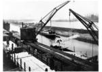 Güterumschlag im Rheinhafen Duisburg-Hochfeld mittels Dampfkran von den Rungenwagen der Reichsbahn auf einen Frachtkahn. Am jenseitigen Rheinufer ist die Silhouette des Krupp-Hüttenwerks Rheinhausen zu erkennen. (1930) <i>Foto: RVM</i>