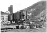 Offener Güterwagen mit Bremserhäuschen in einem Sägewerksanschluss im Schwarzwald. Im Vordergrund die Umlenkrolle einer Spillanlage, um Wagen ohne Verwendung einer Lokomotive verschieben zu können. (1934) <i>Foto: RVM</i>