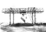 Kipperkatzenverladebrücke der Fa. Demag im Hafen von Wilhelmshaven. In der Originalbeschreibung heißt es:"Zum Zweck der raschen Entladung von Kohlenwaggons wurde die maschinelle Ladeeinrichtung gebaut. Der Brückenkran hebt die Waggons gleichmäßig an und dreht sie zu der Entladestelle. Die Brücke besitzt eine Stützweite von 40 m und eine lichte Höhe von 22 m. Die Kipperkatze ist für eine Nutzlast von 40 t eingerichtet und kann mittels der Kipperplattform 15 Wagen/Std entleeren. Um die Verwendungsfähigkeit der Brücke zu erhöhen und das Verladegut dem Lager entnehmen zu können, ist die Katze mit einem Auslegerarm von 7 m versehen und ein Greiferwindwerk von 20 t Tragkarft eingebaut, wodurch bei Greiferbetrieb eine stündliche Leistung von 150 t erzielt wird." (1930) <i>Foto: RVM</i>