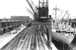 Lagerschuppen im Hamburger Hafen. Am Kai liegt die "Nigerstroom" aus Amsterdam, die eine bewegte Geschichte hinter sich hatte: Das 1939 gebaute Schiff war von 1940-1945 im Dienst der British Ministry of War Transport.Am 01.08.1941 wurde sie auf der Nordsee durch deutsche Flugzeuge beschädigt.Nach einer Kollision auf dem Kanal am 24.08.1946 mit französischen SS "Ernest L. Dawson" wurde sie schwer beschädigt und bis 03.04.1947 in Southampton repariert.In den 1950er Jahren war sie zwischen Europa und Afrika im Einsatz.Am 01.10.1958 fing das Schiff bei einer erneuten Kollision mit der spanischen MS "Monte Urbasa" bei Bordeaux Feuer und sank.Im Dezember 1958 wurde das Wrack verkauft und vor Ort verschrottet. (1954) <i>Foto: Walter Hollnagel</i>