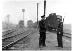 Ein nach Frankreich abgeordneter Reichsbahner der Besoldungsgruppe 11-7a (mit Karabiner) im Bahnschutzdienst unterhält sich mit einem Betriebseisenbahner im Verschiebebahnhof Paris-Trappes. Im Gegensatz zu den "feldgrauen" Eisenbahnern, die bei Feldeisenbahnkommandos zu finden waren, verstärkten diese bewaffeneten Reichsbahner von Fall zu Fall den Bahnschutz, der der Schutzpolizei unterstellt war, allerdings von der Reichsbahn betrieben und unterhalten wurde.  (1944) <i>Foto: RVM (Steiner)</i>