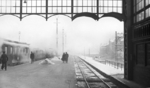 Winterliche Stimmung im Bahnhof Hamburg-Altona. Der Blick geht nach Norden aus der Bahnhofshalle hinaus mit dem Gleis (und der dazugehörigen Oberleitung) der Hafenbahn, die hier in den Tunnel führt. Die Häuser rechts gehören zur Präsident Krahn Straße. (02.1935) <i>Foto: Walter Hollnagel</i>