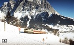 111 099 vor einem Nahverkehrszug von Innsbruck nach Reutte/Tirol vor der Kulisse der Zugspitze bei Leermoos. (04.02.1982) <i>Foto: Peter Schiffer</i>