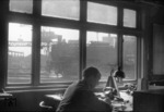 Blick durch die rußgeschwärzten Fenster der Lokleitung des Bw Altona auf 74 705, die gerade eine der beiden Doppeldrehscheiben befährt. Im Hintergund ist der Portaldrehkran der Großbekohlungsanlage zu erkennen.  (11.02.1957) <i>Foto: Walter Hollnagel</i>