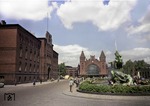 Blick auf den Bahnhofsvorplatz von Hamburg-Altona mit dem Stuhlmannbrunnen. Links das imposante Direktionsgebäude der ehemaligen Königlich-Preußischen Eisenbahn Altona, das in seiner Backsteinbauweise perfekt mit dem Empfangsgebäude harmoniert. Warum nur musste das beeindruckende Ensemble des Altonaer Bahnhofs in den 1970er Jahren einem städtebaulichen Schandfleck per excellence weichen ? Mittlerweile sieht es so aus, dass der Altonaer Bahnhof ganz aus dem Stadtbild verschwinden soll und nur noch unterirdisch für den S-Bahn-Verkehr erhalten bleibt. (07.1957) <i>Foto: Walter Hollnagel</i>