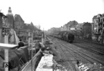 Eine unbekannte 01 rollt stadteinwärts auf dem Ferngleis (Potsdam - Berlin Potsdamer Bahnhof) der Berliner Stammbahn.Über den Wagendächern des Zugendes ist die Bahnsteigüberdachung des S-Bahnhofs Steglitz zu erkennen, bei dem markanten beschädigten Gebäude am linken Bildrand handelt es sich um das Postamt Bergstraße, während das heute noch als Rumpf vorhandene Stellwerk "Szg" (Steglitz Güterbahnhof) wieder instandgesetzt wird. (04.1945) <i>Foto: Walter Hollnagel</i>