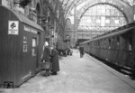 Im kriegszerstörten Lehrter Bahnhof in Berlin suchen zwei Frauen Hilfe beim "Bahnhofsdienst der NSV". Der Bahnhofsdienst der "Nationalsozialistischen Volkswohlfahrt" (NSV) sollte in erster Linie durchreisenden Frauen und Müttern helfen. Dazu gehörten u.a. Essensdienst an den Zügen, Auskunft und Beratung, Bereitstellung von Tagesaufenthaltsräumen für Durchreisende und Beschaffung von Übernachtungsmöglichkeiten. Inwieweit dies noch im Frühjahr 1945 im fast vollständig von der Roten Armee eingeschlossenen Berlin zu leisten möglich war, bleibt dahingestellt. (03.1945) <i>Foto: Walter Hollnagel</i>