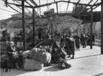 Auch zwei Jahre nach den Kämpfen um die Festungsstadt Sewastopol zeigen sich am Bahnhof noch deutliche Spuren der schwer umkämpften Stadt. Deutsche Soldaten warten auf den Zug, die einzige (russische) Zivilistin ist von dem Fotografen eher peinlich berührt. (1943) <i>Foto: RVM (Hollnagel)</i>