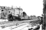 17 007 (Bw Mainz) passiert vor D 161  (Heidelberg - Köln) den Schrankenposten 19 in der nordlichen Bahnhofsausfahrt von Bonn. Links ein Mast der Rheinuferbahn, im Hintergrund die Bahnhofshalle von Bonn. (28.08.1928) <i>Foto: Hermann Maey</i>