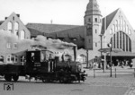 99 5605 der ehemaligen Franzburger Kreisbahn (Lenz-Typ i, Baujahr 1894) überquert den Bahnhofsvorplatz vor dem Stralsunder Hauptbahnhof. Kurz nach der Aufnahme, am 16. Juni 1961 begannen die Züge in Stralsund nicht mehr am Landesbahnhof, sondern an der 2,5 Kilometer entfernten Station Stadtwald, um die Fahrt auf den Straßen der Stadt, vor allem dem Bahnhofsvorplatz, zu vermeiden. (03.1960) <i>Foto: Wolfhard Eschenburg</i>