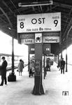 Bereits seit dem 19. Jahrhundert wurden mechanische Zugzielanzeiger auf Bahnsteigen verwendet. Dieses Exemplar stand noch 1970 in Regensburg Hbf. Die mechanischen Zugzielanzeiger sind inzwischen durch modernere und ferngestellte Anzeigetafeln ersetzt worden. Das am Mast des Zugzielanzeigers angebrachte Piktogramm des Kofferkulis weist auf ein System hin, das es seit dem Jahr 2010 bei der DB nicht mehr gibt. Nebenbei: Die 'VIVIL'-Automaten, die Ende der 1950er Jahre entstanden, sind auch Geschichte.  (15.05.1970) <i>Foto: BD Regensburg (Zeitler)</i>