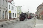 Untrüglich haben die neuen Zeichen der Zeit bereits unmittelbar nach der Wende in Bad Doberan Einzug gehalten. Ein westdeutscher Kaffeeröster wirbt am ehemaligen HO-Laden, während 99 2322 scheinbar unbeeindruckt von dem Umschwung durch die Mollistraße fährt. (13.10.1991) <i>Foto: Will A. Reed</i>