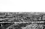 Blick vom Humboldthain auf den Bahnhof Berlin Gesundbrunnen. Vor dem Bahnhof sind auf der Brunnenstraße die damals für Berlin typischen Doppeldecker-Busse der BVG unterwegs. Im Hintergrund verläuft die Swinemünder Brücke über die Gleise und die Häuser des Bezirks Pankow und Prenzlauer Berg. Ein Zug der Ringbahn (ET 165) verlässt den Bahnhof in Richtung Schönhauser Allee. (04.1959) <i>Foto: Jürgen Hagemann</i>