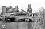 Über die Sektorengrenze an der Oberbaumbrücke fährt ein U-Bahn-Zug mit einem Triebwagen der Bauart AIT mit Stahlwagenkasten (18. Lieferung, Baujahr 1928), einem Triebwagen AIT (13. Lieferung, Baujahr 1913), einem Beiwagen AIB (8. Lieferung, Baujahr 1908) und einem Triebwagen AIT (13. Lieferung, Baujahr 1913). Im April 1960, als dieses Foto entstand, verband die Brücke noch die Bezirke Friedrichshain und Kreuzberg über die Spree. Die U-Bahnlinie B führte von der Station Warschauer Brücke nach Ruhleben im Bezirk Spandau. Mit dem Bau der Berliner Mauer am 13. August 1961 wurde die Oberbaumbrücke für den gesamten Verkehr einschließlich der U-Bahn gesperrt. Zu einer Daueröffnung für Fußgänger kam es ab 1972 durch das Viermächteabkommen über Berlin. Seit 1995 wird die Brücke wieder für die U-Bahn und für den Straßenverkehr genutzt. Die am 23. April 1945 von den Deutschen zerstörten Brückentürme wurden erst nach der deutschen Wiedervereinigung wieder instand gesetzt. (04.1960) <i>Foto: Jürgen Hagemann</i>