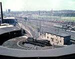Vom Wasserturm aus hatte man einen guten Überblick über den südlichen Teil des Bw Osnabrück Hbf. Direkt vor dem Betrachter liegt der Ringlokschuppen C mit der Drehscheibe, auf der gerade eine 41 Öl gedreht wird. Links hinten befindet sich der Rechteckschuppen A mit der Schiebebühne. Bis 29. September 1968 war das Bw zuständig für die Bespannungen der letzten unter Dampftraktion stehenden Hauptmagistrale in Westdeutschland. Unmittelbar nach Aufnahme des elektrischen Zugbetriebes bis Hamburg endete auch die Dampflokbeheimatung in Osnabrück. (06.1965) <i>Foto: Ulrich Hesse</i>