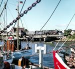 012 102 rollt mit E 1706 nach Hamburg-Altona über die Klappbrücke am Husumer Hafen und wird in Kürze den Bahnhof Husum erreichen. (05.1969) <i>Foto: Ulrich Hesse</i>