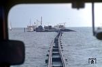 Blick aus dem Triebwagen T 3 der Juistiger Inselbahn auf der Fahrt durchs Wattenmeer zum Schiffanleger. Der Anleger lag etwa 800 Meter vom Festland entfernt, um für tiefergehende Schiffe aus Emden und Norddeich geeignetes Fahrwasser zu erreichen. Nach dem Bau eines ortsnahen Hafens erfolgte 1982 die Stilllegung der Bahn. (04.1971) <i>Foto: Jürgen Hagemann</i>