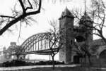 Die Kaiserbrücke (offizieller Name heute: Nordbrücke) wurde am 01. Mai 1904 eingeweiht und verbindet den Mainzer Hauptbahnhof über den Rhein mit Wiesbaden Hbf. Am Ende des Zweiten Weltkrieges 1945 von der abziehenden Wehrmacht gesprengt, wurde 1955 die neue Rheinbrücke als schlichte Gitterträgerkonstruktion errichtet. Auffällig ist die riesige Werbetafel des Brückenherstellers (Brückenbau Union Dortmund), die oben auf dem Brückenbogen installiert wurde - wohl nicht von ungefähr in unmittelbarer Nähe des bekannten Brückenbau-Unternehmens der MAN in Gustavsburg. (1934) <i>Foto: RVM</i>