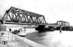 Wegen der beengten Lage des Bahnhofs Stettin zwischen den Stettiner Festungsanlagen und der Oder entstand um 1880 eine neue Drehbrücke nordöstlich des Bahnhofs in direkter Verlängerung der Berliner Strecke. So wurde direkt an den Bahnhof angrenzend in enger Kurve ein gusseiserner Viadukt über die Bollwerkstrasse gebaut, bevor die Strecke über die Oderbrücke (Westoder) die Flussinsel Silberwiese erreicht. Nach der sich anschließenden Viaduktstrecke auf der Insel folgt eine zweite Drehbrücke über die Parnitz, einem Nebenarm der Westoder. Östlich dieser Brücke wurde der Zentral-Güterbahnhof an der Stargarder Strecke angelegt. Das Bild zeigt die Brücke am Hauptbahnhof über die Westoder zur Oderinsel Silberwiese nach dem Umbau. Vor der hinteren Fachwerkbrücke steht des Einfahrvorsignal vom Bahnhof Stettin Gb. Im Hintergrund ist die städtische Hansa-Brücke zu erkennen, deren Mittelteil als Klappbrücke fungiert.  (1937) <i>Foto: RVM</i>