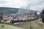 Prägend für das kleine Dorf Paulinzella ist das Kloster, das um 1102 durch die Benediktinerinnen gegründet wurde (sichtbar oberhalb der Zuglok). 44 0221 und Schublok 44 0663 ballern mit einem Umleitergüterzug durch den Ort. (14.04.1977) <i>Foto: Joachim Bügel</i>