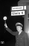 Der Aufsichtsbeamte war für alle Aufgaben, die mit dem Herstellen und Feststellen der Abfahrbereitschaft eines Zuges und dem Erteilen des Abfahrauftrages zusammenhängen, zuständig. Seine rote Mütze hatte den Sinn, allen beteiligten Mitarbeitern am Zug klar anzuzeigen, wer hier das Sagen hat, also um Irrtümern in der Kommunikation vorzubeugen. Das Bild entstand im nächtlichen Bahnhof Altona. (02.1957) <i>Foto: Walter Hollnagel</i>