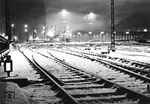 Weihnachtsstimmung im Kölner Hauptbahnhof. Der Blick geht von der Hohenzollernbrücke auf die Ausfahrsignale der Ostausfahrt und den im Dunkeln liegenden Dom (links). Abfahrbereit an den beiden Gleisen des südlichsten Inselbahnsteigs steht eine 01 und eine leider nicht eindeutig zu identifizierende preußische Lok (P8, T18 oder T14.1) ohne Windleitbleche, die offenbar - nach den Lichtstreifen der Laternen - zunächst ausfahren oder vorrücken durfte. (12.1937) <i>Foto: RBD Köln (Felten)</i>
