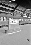 Werbung für das Bahnhofskino (Bali = Bahnhofslichtspiele) in Hagen Hbf. In ständiger Wiederholung zeigten diese eine 50 Minuten lange Zusammenstellung aus Beiträgen verschiedener Wochenschauen, ein bis zwei Kulturfilmen und einem Zeichentrick- oder Slapstickfilm. Der Eintrittspreis betrug seit 1953 einheitlich für alle Plätze 50 Pfennig. Später setzte man mehr auf reißerische Filme und schließlich seit Ende der 1970er Jahre vollständig auf Sex- und Actionfilme. Mit dem Niveau der dargebotenen Filme sank auch das Ansehen der Kinos, und spätestens Ende der 1970er Jahre hatte sich der schlechte Ruf manifestiert. Bahnhofskinos passten bald nicht mehr in das Konzept der Bundesbahn, die daranging, Bahnhöfe in Kaufhäuser mit Gleisanschluss umzuwandeln. 1990 waren noch sechs Bahnhofkinos in Betrieb, 1999 schloss das letzte. Auch der vermeintlich unscheinbare Speisewagen im Hintergrund ist eine nähere Betrachtung wert: Es zeigt eine der wenigen kompletten küchenseitigen Ansichten des Speisewagens "DSG 1230", der 1952 aus dem Rheingold-Salonspeisewagen SA4ük 10 501 der alten 1. Klasse zum Einsatz als luxuriöser Stammspeisewagen eigentlich im "Blauen Enzian"-Gegenzug umgebaut wurde. Warum dieser Wagen in Hagen weit außerhalb seines üblichen Laufweges angetroffen wurde, ist unklar. (24.07.1956) <i>Foto: BD Wuppertal (Säuberlich)</i>