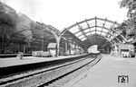 Im Bahnhof Wuppertal-Elberfeld (heute Hbf) präsentiert sich die 70 Jahre alte Bahnhofshalle letztmalig noch halbwegs vollständig. Nachdem die Halle beim schweren Bombenangriff auf Elberfeld am 24.06.1943 stark in Mitleidenschaft gezogen worden war und nur provosorisch in einem Teilbereich wiederhergestellt werden konnte, entschloss sich die BD Wuppertal im Zuge des Modernisierungsprogramms Anfang der 1960er Jahre zum Komplettabriss. Links dampft 86 872 vom Bw Wuppertal-Langerfeld. (08.09.1961) <i>Foto: Helmut Säuberlich</i>