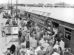 Reisende an einem Dostozug nach Potsdam auf dem Fernbahnsteig in Berlin-Schönefeld. An heißen Sommertagen war die Fahrt im oberen Stockwerk wohl kein Vegnügen. (1964) <i>Foto: Historische Sammlung der Deutschen Bahn AG</i>