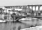 Das Göhrener Viadukt (Muldentalbrücke) an der Bahnstrecke Neukieritzsch–Chemnitz im Ortsteil Göhren, südlich von Wechselburg in Sachsen gehört neben der Elster- und Göltzschtalbrücke zu den eindrucksvollsten deutschen Brückenbauten aus der Frühzeit des Eisenbahnbaues. Sie überspannt das Tal der Zwickauer Mulde mitsamt der Muldentalbahn mit einer Höhe von 68 Metern, teilweise in zwei Etagen. Die Länge beträgt 381 m, ursprünglich 512 m mit 12 (ursprünglich 21) Öffnungen oben, die größte Spannweite eines Bogens beträgt 16 m. Das Mauerwerk nimmt ein Volumen von 55.514 m³ ein. Durch Verfüllung der Bögen an den Enden des Viadukts wurde die Brücke bei Sanierungsarbeiten zwischen 1982 und 1986 auf 381 m verkürzt. Über das Viadukt fährt gerade eine P 8. Die Grundsteinlegung erfolgte am 27. Mai 1869, die Fertigstellung im Juni 1871. Die Baukosten der Brücke betrugen 1,2 Millionen Taler (3,6 Millionen Reichsmark).  (14.02.1959) <i>Foto: Gerhard Illner</i>