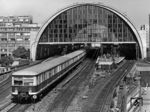 Ein S-Bahnzug nach Erkner verlässt den Bahnhof Berlin-Alexanderplatz. 1964 wurde der Bahnhof nach Entwürfen der Architekten Hans Joachim May und Günter Andrich dem am Alexanderplatz entstehenden sozialistischen Stadtbild angepasst. Die Seitenwände erhielten eine schlichte hohe Verglasung und der Unterbau wurde mit Granit verblendet. Außerdem benutzte nun die S-Bahn auch eine Seite des seit 1942 außer Betrieb befindlichen Fernbahnsteigs, der hierfür von 70 auf 96 Zentimeter erhöht wurde. Seitdem war eine wesentlich flexiblere Betriebsführung möglich. (06.07.1985) <i>Foto: Burkhard Sprang</i>