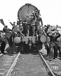 "Anti-Kommunistische Demonstranten erobern einen sowjetischen Arbeitszug in Berlin-Neukölln und jagen 4 russische Transportoffiziere mit 30 kommunistischen Streikbrechern davon, die Weichen reparieren wollten" - so der offizielle Pressetext des amerikanischen Fotografens. Andere Quellen sprechen hingegen von streikenden Westberliner Reichsbahnern, die hier gegen die schlechten Arbeitsbedingungen und die Bezahlung in Ost-Mark protestieren. Bei genauer Betrachtungsweise scheint es sich bei den abgebildeten Herren jedoch nicht um die streikenden West-Eisenbahner zu handeln, sondern vielmehr um deren Gegenspieler aus dem kommunistischen Lager (Uniformen, rote Fahne). Bei der "eroberten" Lok handelt es sich übrigens um 52 1465 vom Bw Schöneweide. Der Zug steht an der Grenze zwischen den Verwaltungsbezirken Treptow und Neukölln, und damit genau an der Grenze zwischen dem damaligen sowjetischen und amerikanischen Sektor Berlins.  (30.05.1949) <i>Foto: Al Cocking (ACME)</i>