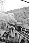 Über das Stadtviadukt in Lauscha macht sich 95 0014 mit ihrem Güterzug auf den Weg nach Oberlauscha. Der Zug wird jetzt den Berg Teufelsholz umrunden und dabei auf einer Strecke von etwa 3,3 km durch den Lauschensteintunnel und über das Viadukt Nasse Telle den Bahnhof Lauscha in nur etwa 330 m Luftlinie wieder passieren und hat dabei etwa 85 Höhenmeter gewonnen. (06.04.1977) <i>Foto: Joachim Bügel</i>