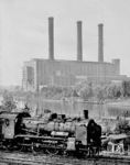 Vor dem Kraftwerk Ernst Reuter (ehem. Kraftwerk West) im Berliner Ortsteil Siemensstadt ist vermeintlich eine P 8 des Bw Lehrter Bf unterwegs. Zwischen der Bahntrasse und dem Kraftwerk liegt die Spree. In diesem Abschnitt am Wiesendamm befanden sich früher zwei Gleispaare: nördlich die Vorortbahn Lehrter Bahnhof - Jungfernheide - Fürstenbrunn - Spandau Hbf - Spandau West, südlich die Fernbahn Lehrter Bahnhof - Spandau Hbf - Stendal - Oebisfelde - Lehrte bzw. Spandau Hbf - Hamburg. Das nördlich gelegene Gleispaar bzw. das verbliebene Einzelgleis Jungfernheide - Fürstenbrunn - Spandau Hbf wurde bereits 1951 auf elektrischen S-Bahn-Betrieb umgestellt, um nicht mehr mit Dampflokomotiven fahren zu müssen. Zuständig für die Lokomotivgestellung auf dieser Strecke war u.a. das Bw Lehrter Bhf, das im Juli 1952 seine P8-Zeit beendete. Der Personenzugverkehr auf dem verbliebenen südlichen Einzelgleis zum Lehrter Bahnhof wurde ebenfalls bereits 1951 eingestellt. Die Lok fährt von West nach Ost nahe des Wiesendamms zwischen Berlin-Ruhleben Gbf und Berlin Jungfernheide. (1950) <i>Foto: Pressefoto ACME</i>