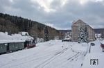 99 1590 hat den Bahnhof Jöhstadt erreicht. Der Bahnhof war früher der Betriebsmittelpunkt der Preßnitztalbahn. Hier befand sich neben umfangreichen Abstellgleisen auch ein dreiständiger Lokschuppen, welcher die Lokomotiven der Strecke beheimatete. Nach der Stilllegung des oberen Abschnittes im Januar 1984 begann im Sommer 1985 der Abriss der Anlagen. 1987 begann der Bau eines Wohnblocks auf dem Bahnhofsgelände (rechts), das Empfangsgebäude wurde fortan als Kindertagesstätte genutzt. Nach 1990 wurde ein Teil der Gleisanlagen durch die IG Preßnitztalbahn für den Museumsbahnbetrieb wieder aufgebaut. (15.01.2017) <i>Foto: Joachim Schmidt</i>