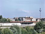 Vor der Kulisse des Ostberliner Fernsehturms wechselt eine S-Bahn über die "Staatsgrenze" zwischen West- und Ost-Berlin. Obwohl an einem "normalen" Tag etwa 2300 Soldaten direkt an der Grenze und im grenznahen Raum eingesetzt waren, gelangen zwischen dem 13. August 1961 und dem 9. November 1989 noch 5075 Fluchten nach West-Berlin. Über die Zahl der Mauertoten gibt es widersprüchliche Angaben. Bis heute gibt es keine verlässliche Zahlen, weil die Todesfälle an der Grenze von den Verantwortlichen der DDR-Staatsführung systematisch verschleiert wurden. Die Berliner Staatsanwaltschaft gab im Jahr 2000 die Zahl der nachweislich durch einen Gewaltakt an der Berliner Mauer umgekommenen Opfer mit 86 an. Wie schwierig genaue Aussagen auf diesem Gebiet sind, wird auch dadurch deutlich, dass die Arbeitsgemeinschaft 13. August ihre Zahl der Mauertoten seit 2000 von 238 auf 138 korrigieren musste. (26.08.1979) <i>Foto: Johannes Glöckner</i>