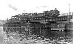 Wegen der beengten Lage des Bahnhofs Stettin zwischen den Stettiner Festungsanlagen und der Oder entstand um 1880 eine neue Drehbrücke nordöstlich des Bahnhofs in direkter Verlängerung der Berliner Strecke. Wegen der beengten Raumsituation waren eine Reihe von Kunstbauten nötig. So wurde direkt an den Bahnhof angrenzend ein gemauertes Viadukt über die Zufahrtsstraße von der Stadt zum Bahnhof gebaut, bevor die Strecke nach einer engen Kurve die eigentliche Oderbrücke erreichte. Jenseits der Oder schloss sich erneut ein Viadukt über einige Straßen an. Weiter östlich entstand eine weitere Brücke über die Parnitz, einen Nebenarm der Oder. Östlich der Parnitz wurde der neue Güterbahnhof gebaut, durch den die Hauptgleise der Stargarder Strecke verliefen. Hier überquert 38 3244 (Bw Stettin Hbf) die Drehbrücke kurz vor dem Stettiner Hauptbahnhof. (1936) <i>Foto: DLA Darmstadt (Bellingrodt)</i>