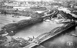 Blick auf die zwischen Veddel und Rothenburgsort gelegenen Norderelbebrücken in Hamburg. Die Straßenbrücke über die Norderelbe (im Vordergrund) wurde zwischen 1884 und 1887 mit charakteristischen Fischbauchträgern nach dem System Lohse als "Neue Norderelbbrücke" gebaut - zur Unterscheidung von der flussabwärts gelegenen Eisenbahnbrücke von 1872. Beim Ausbau der Norderelbbrücke zwischen 1928 und 1929 wurde der filigranen ersten Konstruktion eine zweite vollwandig ausgeführte Brücke hinzugefügt. Von 1957 bis 1960 erfolgte eine umfassende Verbreiterung, wobei die neugotischen Portale und die westliche Originalbrücke von 1887 abgerissen wurden. Die Eisenbahnbrücke (oben) besteht aus zwei separaten Brücken. Die erste Norderelbbrücke wurde 1868–1872 für die Hamburg-Venloer Bahn der Köln-Mindener Eisenbahn-Gesellschaft gebaut. Die Brückenbaugesellschaft Harkort in Duisburg war mit der Errichtung der zweigleisigen Brücke beauftragt, die architektonische Gestaltung oblag Heinrich Strack. Die eisernen Überbauten wurden zwischen 1890 und 1893 von zwei auf vier Gleise erweitert. Dabei wurden auch die Portale erweitert. Von 1926 bis 1927 wurden die Brückenträger durch stärkere Neubauten ersetzt. Die Gestaltung der neuen Brücke lehnte sich an die gerade fertiggestellte Freihafenbrücke an.  (1930) <i>Foto: RVM</i>