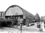 Für die ab 1875 gebaute Berliner Stadtbahn wurde nach Entwürfen von Johann Eduard Jacobsthal von 1881 bis 1882 am Alexanderplatz der gleichnamige Bahnhof errichtet. Der Bau erfolgte auf dem zugeschütteten Königsgraben, einem ehemaligen Festungsgraben Alt-Berlins. Der Bahnhof wurde als viergleisiger Durchgangsbahnhof mit Mittelbahnsteigen angelegt und mit einer 164 Meter langen, halbrunden Bahnsteighalle ausgestattet. Die meisten Betriebsräume des Bahnhofs wurden in den gemauerten Viaduktbögen untergebracht. Auf der Ostseite des Bahnhofs errichtete man zusätzlich einen an den Enden überkuppelten zweigeschossigen Vorbau. Die ersten Züge im Vorortverkehr hielten am 7. Februar 1882 im Bahnhof Alexanderplatz, die ersten Fernzüge gut drei Monate später zum Fahrplanwechsel am 15. Mai. Das Bild zeigt den Zustand des Bahnhofs um 1905 mit der Königstraße (vorne) und dem Eingang von der Dirksenstraße aus.  (1905) <i>Foto: RVM-Filmstelle Berlin</i>