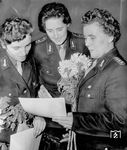 Die ersten 3 E-Lokführerinnen der RBD Halle (von links nach rechts) Edith Leipholz, Ruth Ewert, Anni Rausch haben nach erfolgreicher Prüfung ihre Urkunden erhalten. Frau Rausch war auch nochmal im aktiven Dienst "Werbegesicht" für den neuen Beruf der Lokführerinnen bei der Reichsbahn (vgl. Bild-Nr. 31560). Zu Ihrem 80. Geburtstag am 10. April 1995 erschien ein Zeitungsartikel, der auch Ihren ungewöhnlichen Lebensweg beschrieb: Als eines von 16 (!) Geschwistern musste sie sich nach dem Tod der Eltern als Vollwaise früh durchsetzen. Schon in den 1930er Jahren war sie als Maschinistin im Braunkohlewerk Edderitz (zwischen Köthen und Halle) in einer damals ausschließlichen Männerdomäne tätig. Als das Braunkohlewerk 1956 geschlossen wurde, hörte sie von zwei ihrer Schwestern, dass die Reichsbahn auch Frauen als Lokführerin zuließ. Ihre "Jungfernfahrt" bestritt sie 1960 und fuhr 18 Jahre lang unfallfrei auf E-Loks. (23.10.1961) <i>Foto: Historische Sammlung der Deutschen Bahn AG</i>