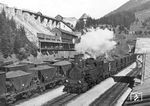 BBÖ 69.10 fährt mit einer Schiebelok und einen beladenen Erzzug in den Bahnhof Prebichl in der Obersteiermark ein. Im Hintergrund befindet sich die alte Erzverladeanlage. Zwischen 1888 und 1891 baute man die normalspurige Zahnradbahn vom bisherigen Endbahnhof Eisenerz (692 m) von der Hauptbahn Hieflau—Eisenerz über den Erzberg und Prebichl-Pass (1204 m) zum bisherigen Endbahnhof Vordernberg (768 m) an der Strecke von Leoben. Die etwa 19 Kilometer lange Zahnradbahn vereinfachte den Erztransport in südliche Richtung wesentlich. Gleichzeitig mit der Fertigstellung der Strecke wurde im Hüttenwerk Donawitz der ÖMAG ein moderner Kokshochofen zur Versorgung des SM-Stahlwerkes mit Roheisen angeblasen. Das Beladen der Erzzüge für Donawitz erfolgte im Bahnhof Eisenerz in 1.070 m Seehöhe. Die Zahnradlokomotiven unterstanden der Heizhausleitung (Hhl) Vordernberg. BBÖ 69.10 erhielt wenig später die neue DRB-Nummer 97 210. Die Schreibweise des Bahnhofs Prebichl wurde übrigens erst zum 1. Jänner 1957 in "Präbichl" geändert.  (1938) <i>Foto: RVM</i>