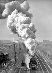 Blick von der Putlitzbrücke in Richtung Westen auf 52 5864 (Bw Berlin-Pankow), die am Moabiter Güterbahnhof (links) vorbeifährt. Die Berliner Ringbahn verläuft in diesem Bereich etwa in west-östlicher Richtung. Ihre S-Bahngleise, die nicht zum Bahnhof Moabit gehören, bilden am rechten Bildrand die nördliche Grenze des Bahnhofs, südlich des Güterbahnhofs der Station liegen die Siemensstraße und die Quitzowstraße. Das Westende des Bahnhofs befindet sich westlich des S-Bahnhofs Beusselstraße, in Richtung Osten reicht der Bahnhof über den S-Bahnhof Putlitzstraße (heute Westhafen) hinaus. Im Bahnhof Moabit nimmt die Kilometrierung der Ringbahn ihren Ausgangspunkt (km 0,0). Die Trasse der Hamburger und Lehrter Bahn fädelt sich hier parallel zur Ringbahn aus und schwenkt im Osten des Bahnhofs Moabit zum ehemaligen Lehrter Bahnhof (heute Berlin Hauptbahnhof tief) in Richtung Südosten von der Ringbahn ab. In Richtung Westen trennen sich die Strecken im Bereich Jungfernheide. Ein Gleis der alten Bahnstrecke zum Lehrter Bahnhof führt heute noch vom Bahnhof Moabit zum ehemaligen Hamburger und Lehrter Güterbahnhof, um über eine Stichfahrt die Gleisanlagen des Westhafens erreichen zu können. In Richtung Berlin Hauptbahnhof tief ist seit 2006 die Neubaustrecke der Nord-Süd-Fernbahn in Betrieb. (03.1948) <i>Foto: Max Ittenbach</i>