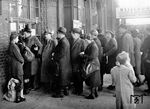 Andrang an der provisorischen Fahrkartenausgabe in Kassel Hbf. Nach den Zerstörungen im Zweiten Weltkrieg wurde das Bahnhofsgebäude erst von 1952 bis 1960 unter Beibehaltung der historischen Substanz auf der Bahnsteigseite wieder aufgebaut. Die Reisenden scheinen Fahrkarten für Hamsterfahrten ins Umland zu lösen. Da die auf Lebensmittelkarten zu kaufende Nahrung bei weitem nicht ausreichte, konnten sich die Menschen in den Städten nur durch Tausch- und "Kompensationsgeschäfte" das Überleben sichern. So fuhren sie massenhaft aufs Land, wo die Versorgungslage deutlich besser war, um Butter, Speck, Kartoffeln gegen Hausrat, Kleidung oder Wertgegenstände zu tauschen. (1946) <i>Foto: Helmut Först</i>